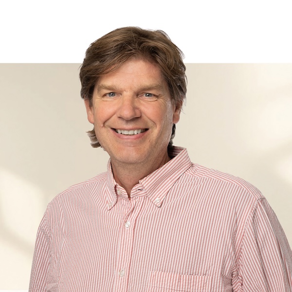 Porträt von Marco Spies mit mittellangen, braunen Haaren und rot-weiss gestreiftem Hemd vor neutralem, unscharfem Hintergrund