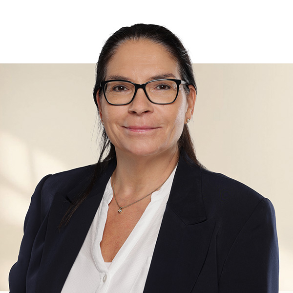 Porträt von Pia Vedova mit dunklen, glatten Haaren, Brille, weissem Hemd und dunkelblauem Blazer vor hellem, neutralem Hintergrund